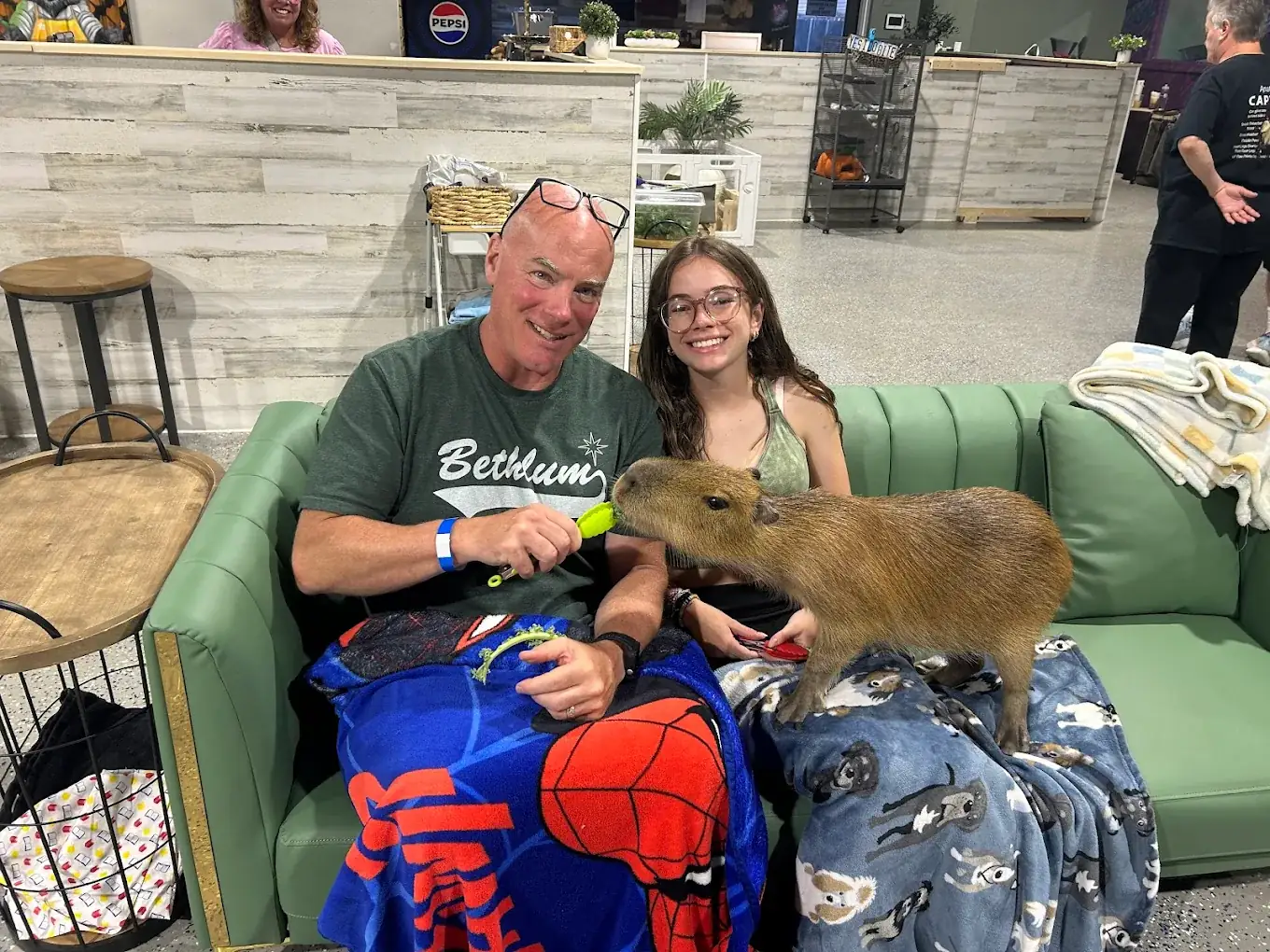 A father and daughter sharing the sofa with a capybara at Capybara Cafe St. Petersburg